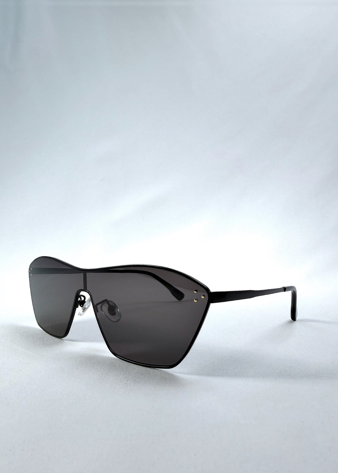 Three-quarter front view of Atlas Shield sunglasses in Slate Smoke, featuring one-piece shield lens, slim metal frame, and full grey tint, showing the front shape and temple profile. 