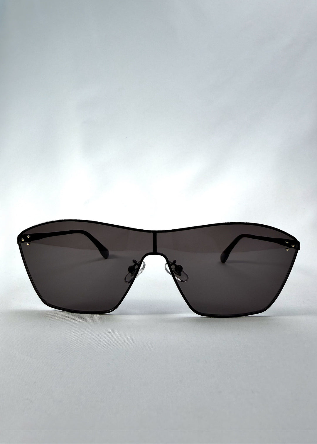 Front view of Atlas Shield sunglasses in Slate Smoke, featuring one-piece shield lens, slim metal frame, and full grey tint, showing the full front silhouette. 