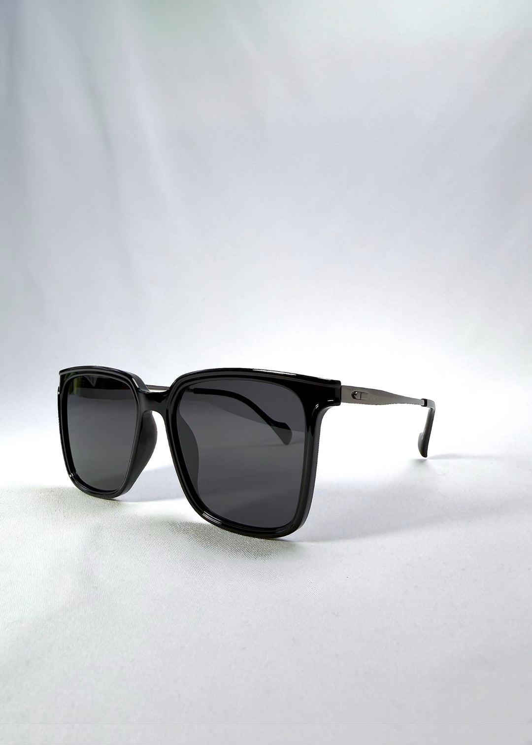 Three-quarter front view of Auralis sunglasses in Duskgold, featuring black and gold frame with dark lenses, showing the front shape and temple profile.