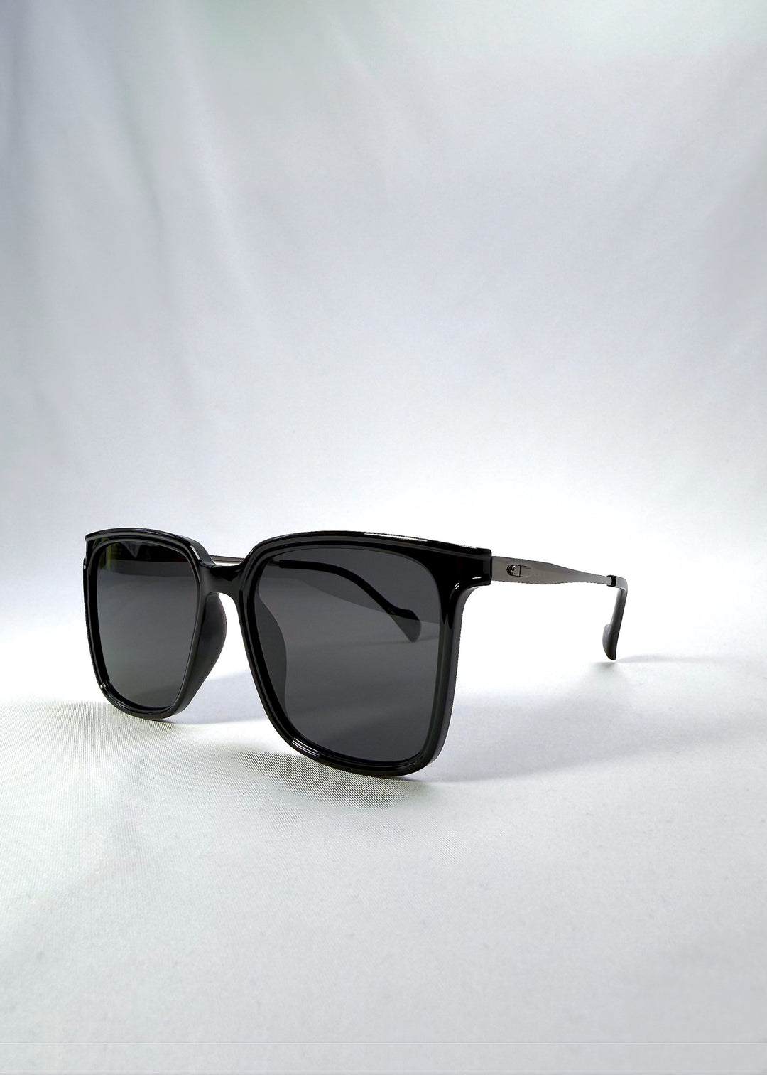 Three-quarter front view of Auralis sunglasses in Duskgold, featuring black and gold frame with dark lenses, showing the front shape and temple profile. 