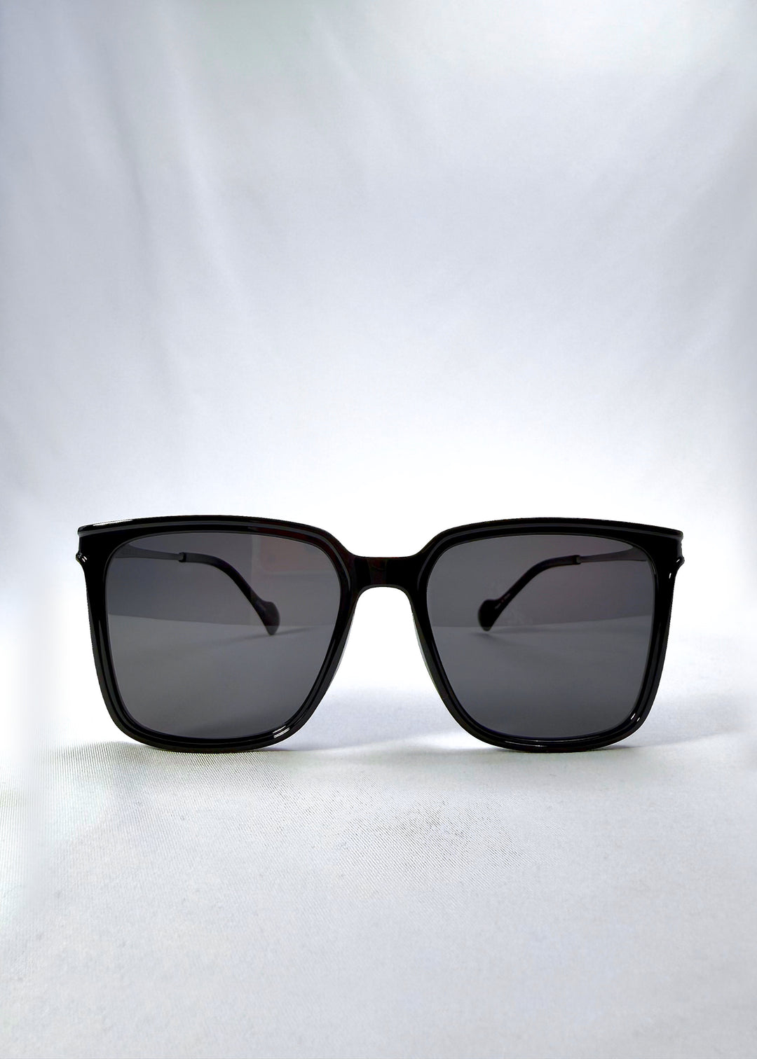 Front view of Auralis sunglasses in Duskgold, featuring black and gold frame with dark lenses, showing the full front silhouette.