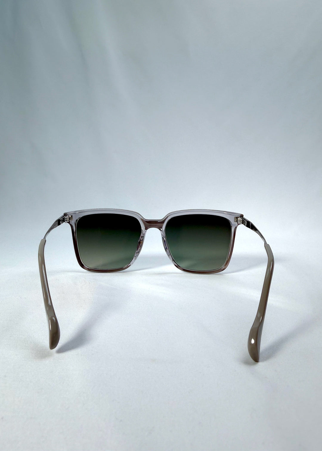 Back view of Auralis sunglasses in Rose Graphite, featuring rose graphite frame and green gradient lenses, showing the inside frame and open temples.