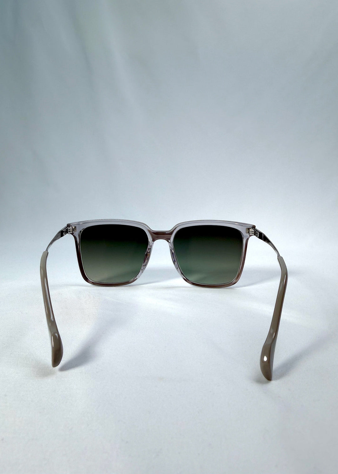 Back view of Auralis sunglasses in Rose Graphite, featuring rose graphite frame and green gradient lenses, showing the inside frame and open temples. 