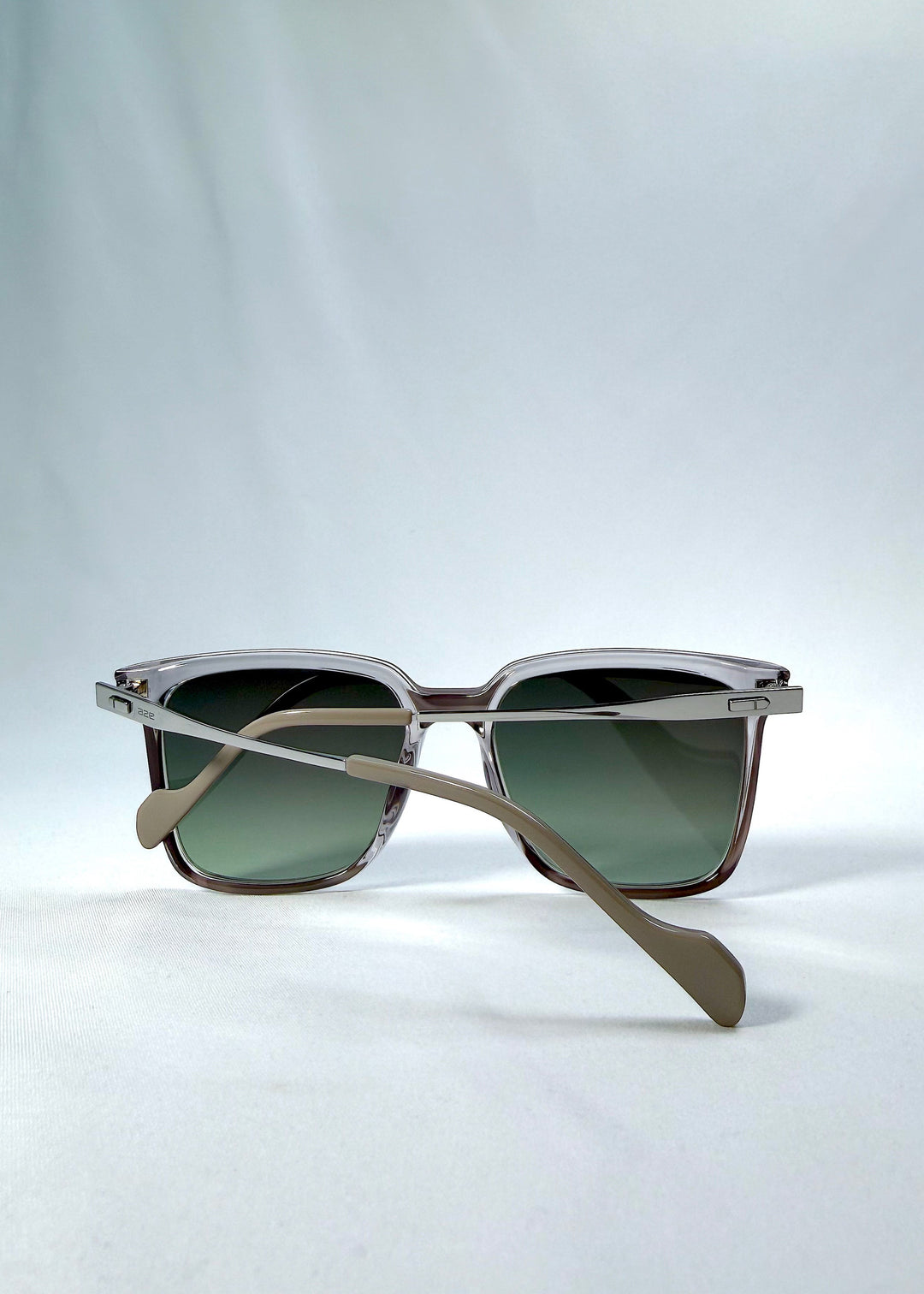 Folded back view of Auralis sunglasses in Rose Graphite, featuring rose graphite frame and green gradient lenses, showing the folded temples and back structure. 