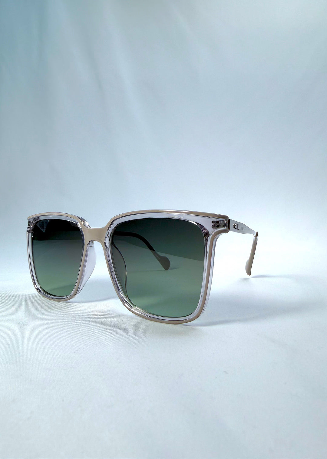 Three-quarter front view of Auralis sunglasses in Rose Graphite, featuring rose graphite frame and green gradient lenses, showing the front shape and temple profile.