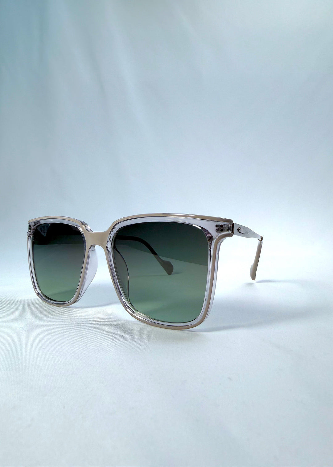 Three-quarter front view of Auralis sunglasses in Rose Graphite, featuring rose graphite frame and green gradient lenses, showing the front shape and temple profile. 