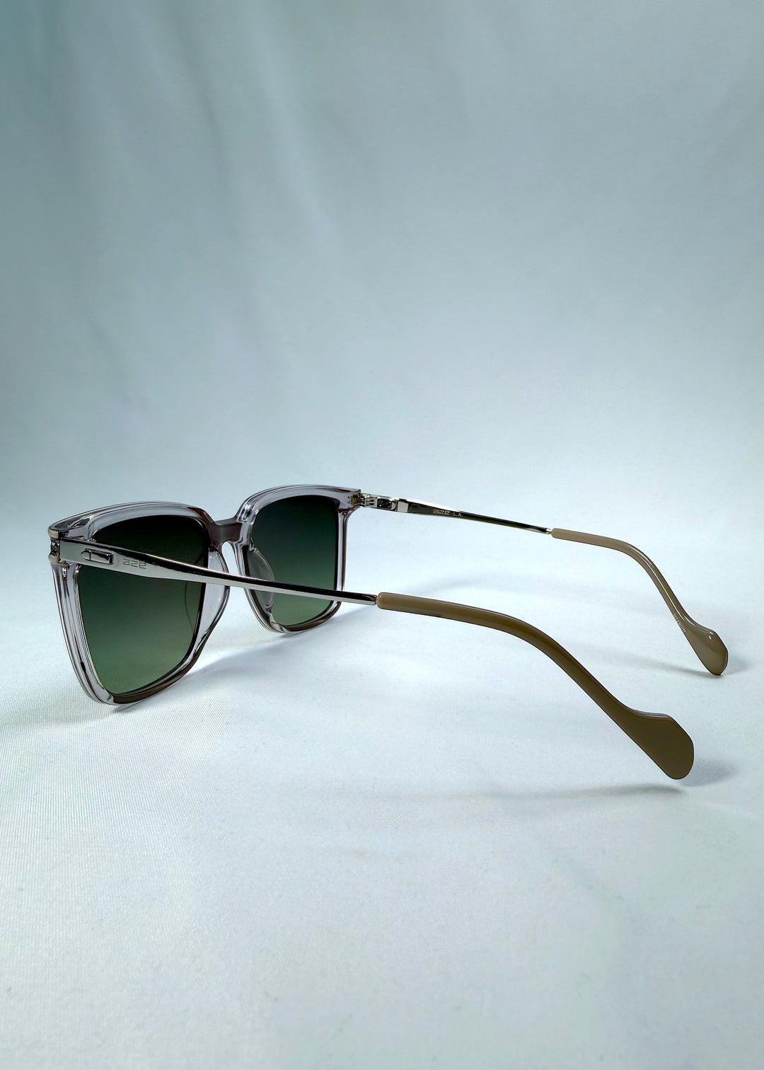 Side-angle view of Auralis sunglasses in Rose Graphite, featuring rose graphite frame and green gradient lenses, showing the lens shape and side temple profile.