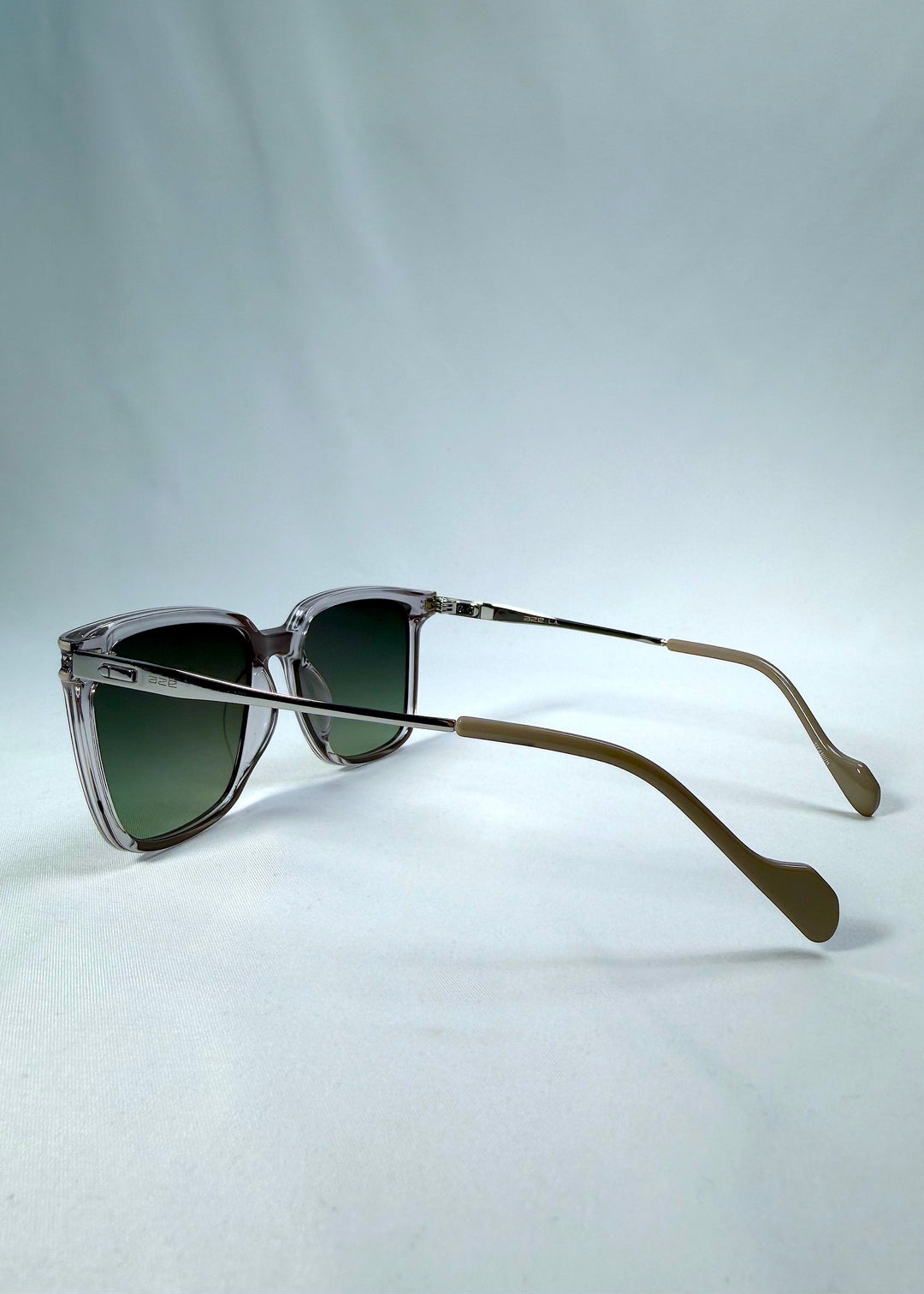 Side-angle view of Auralis sunglasses in Rose Graphite, featuring rose graphite frame and green gradient lenses, showing the lens shape and side temple profile. 
