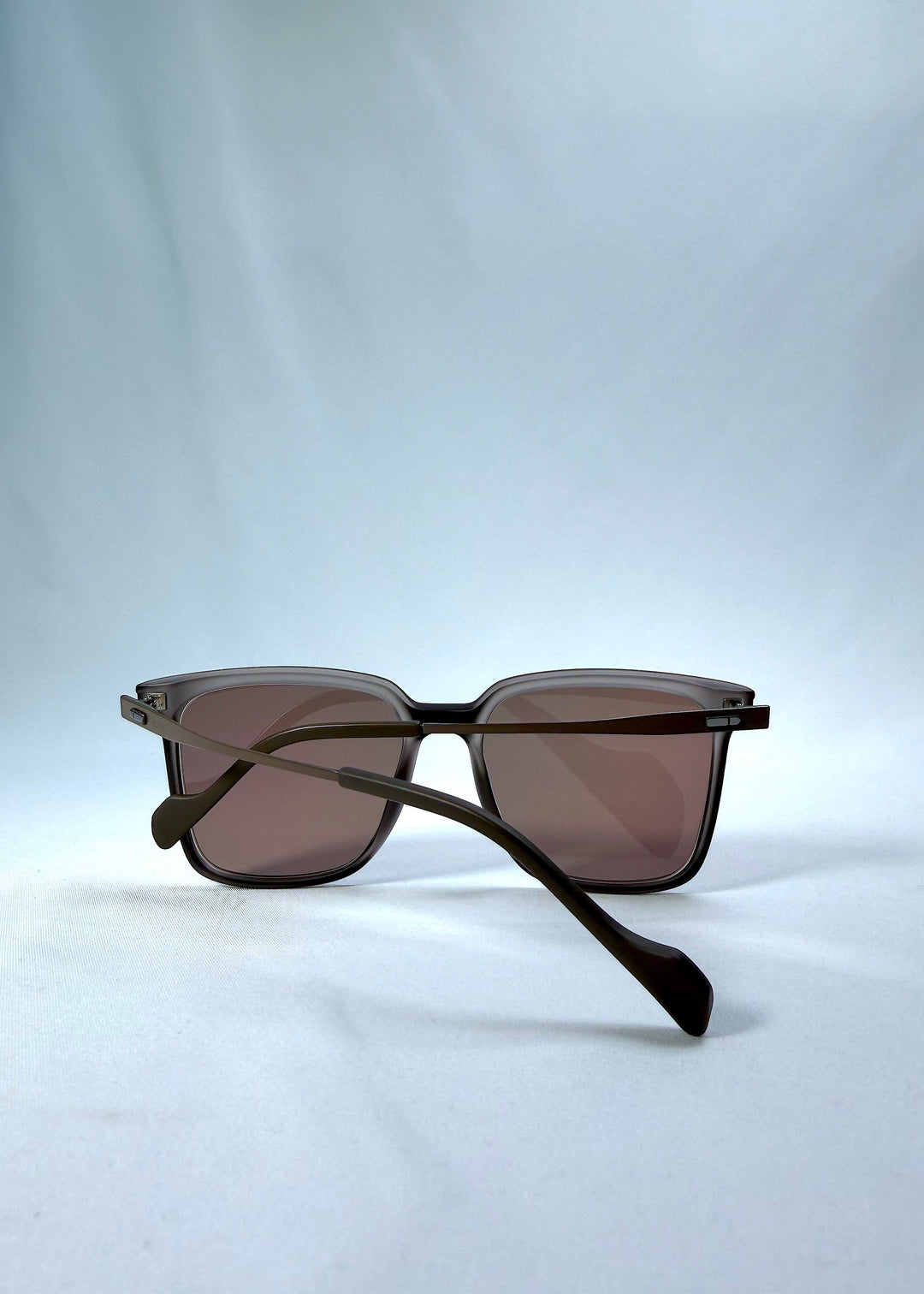 Folded back view of Auralis sunglasses in Sand Amber, featuring sand amber frame and brown lenses, showing the folded temples and back structure. 