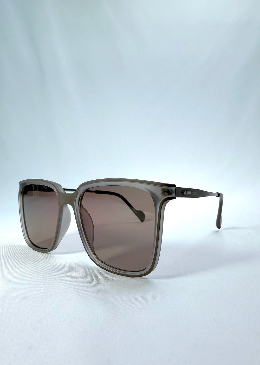 Three-quarter front view of Auralis sunglasses in Sand Amber, featuring sand amber frame and brown lenses, showing the front shape and temple profile.