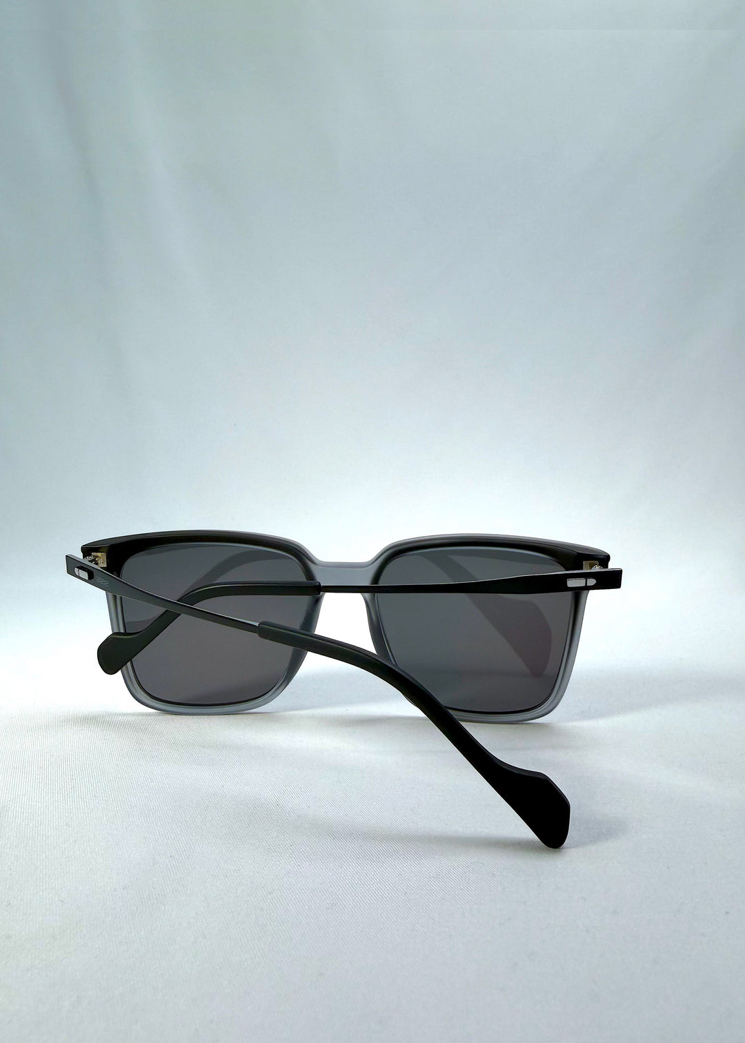 Rear folded view of Auralis sunglasses in Sand Haze showing the crossed temples behind the lenses. 