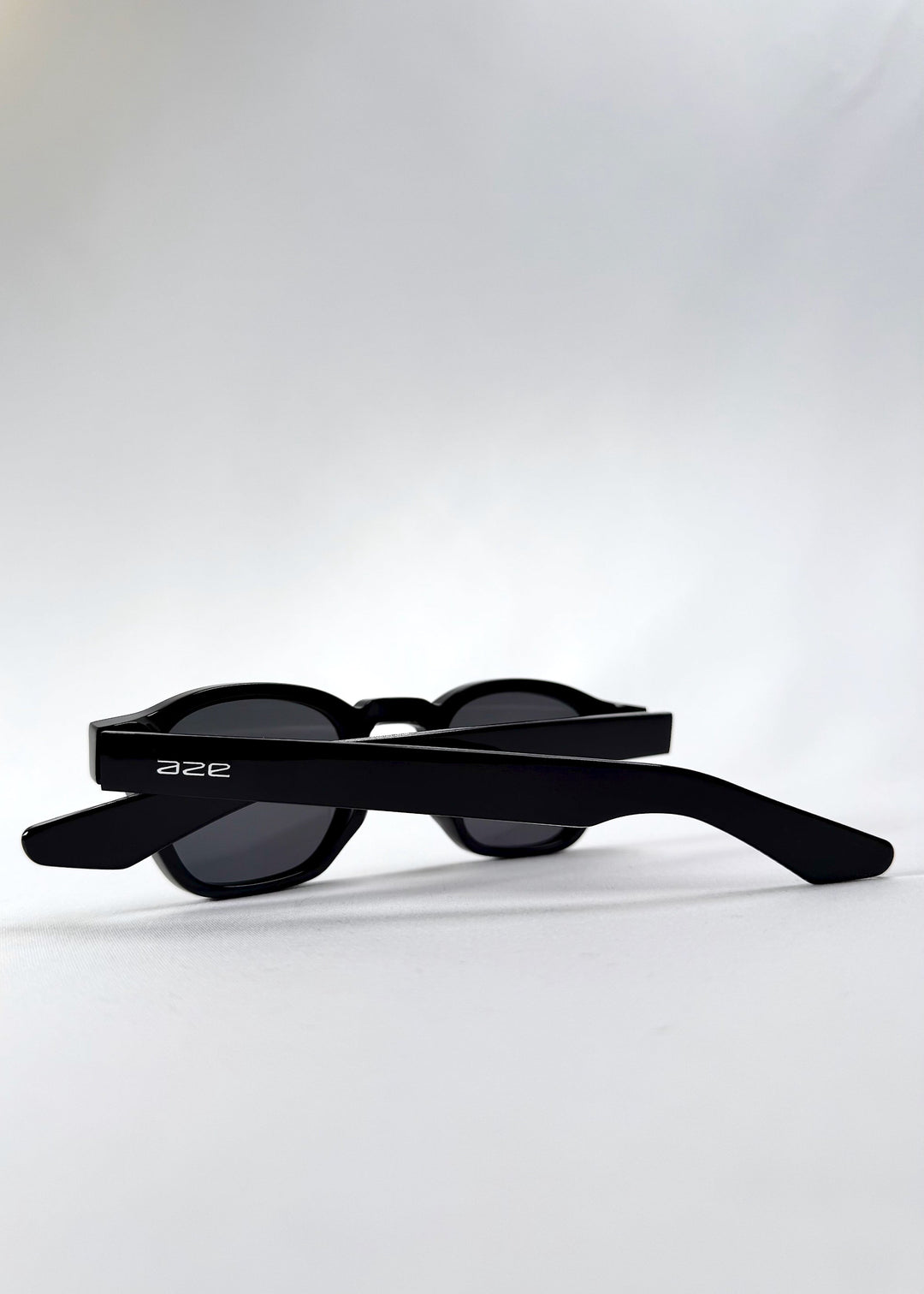 Folded back view of Auren Black sunglasses displaying wide temples and compact sizing. 