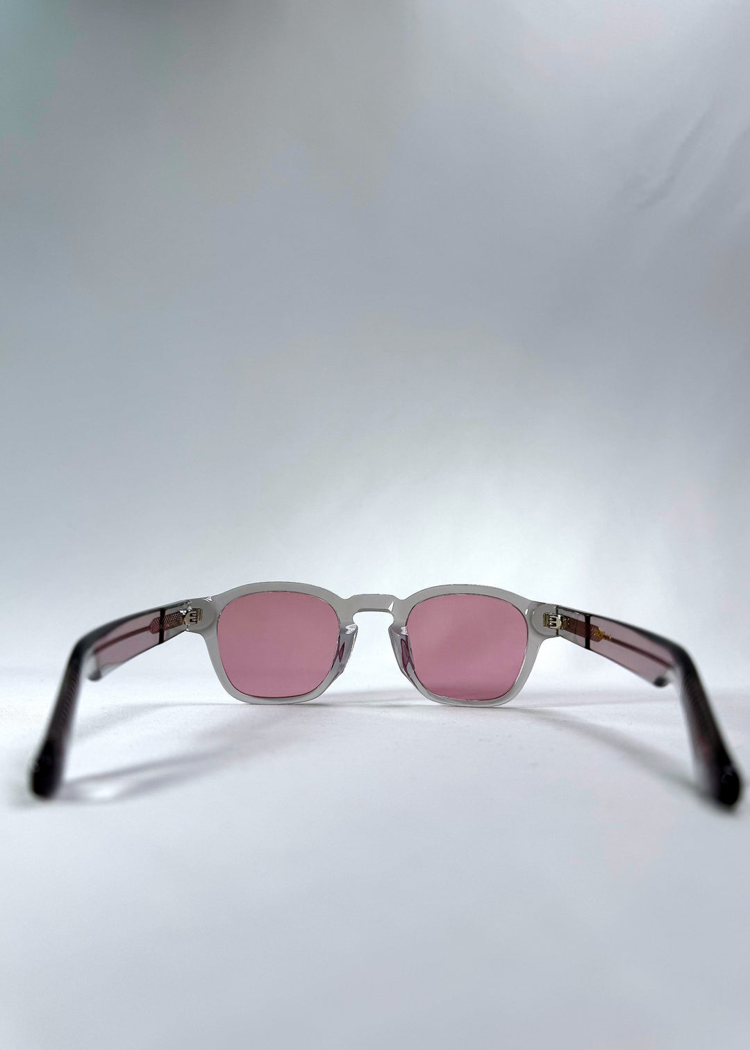 Back view of Auren Blush Grey sunglasses displaying the transparent temple arms and interior blush tint. 