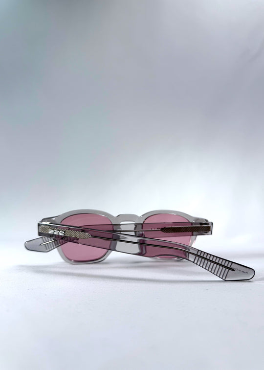 Folded Auren Blush Grey sunglasses showcasing the clean acetate structure and AZE branding on temples.

