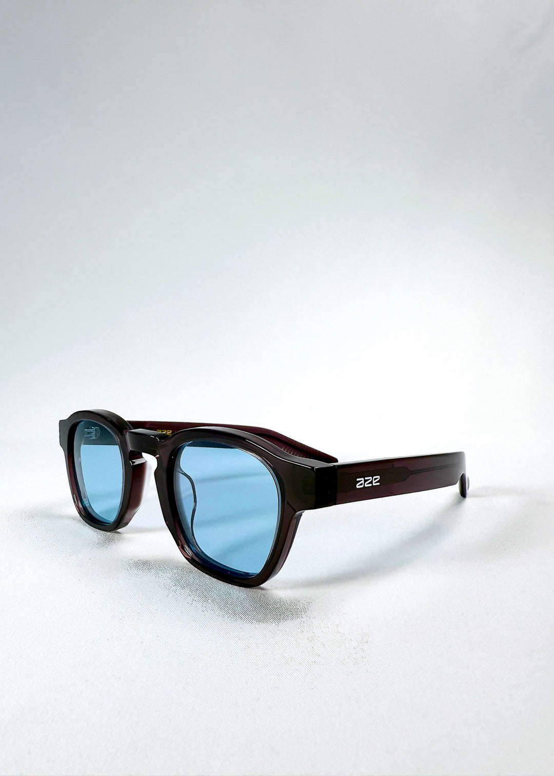 Front-angle view of Auren Mahogany Smoke sunglasses showcasing the curved silhouette and soft blue lens contrast. 