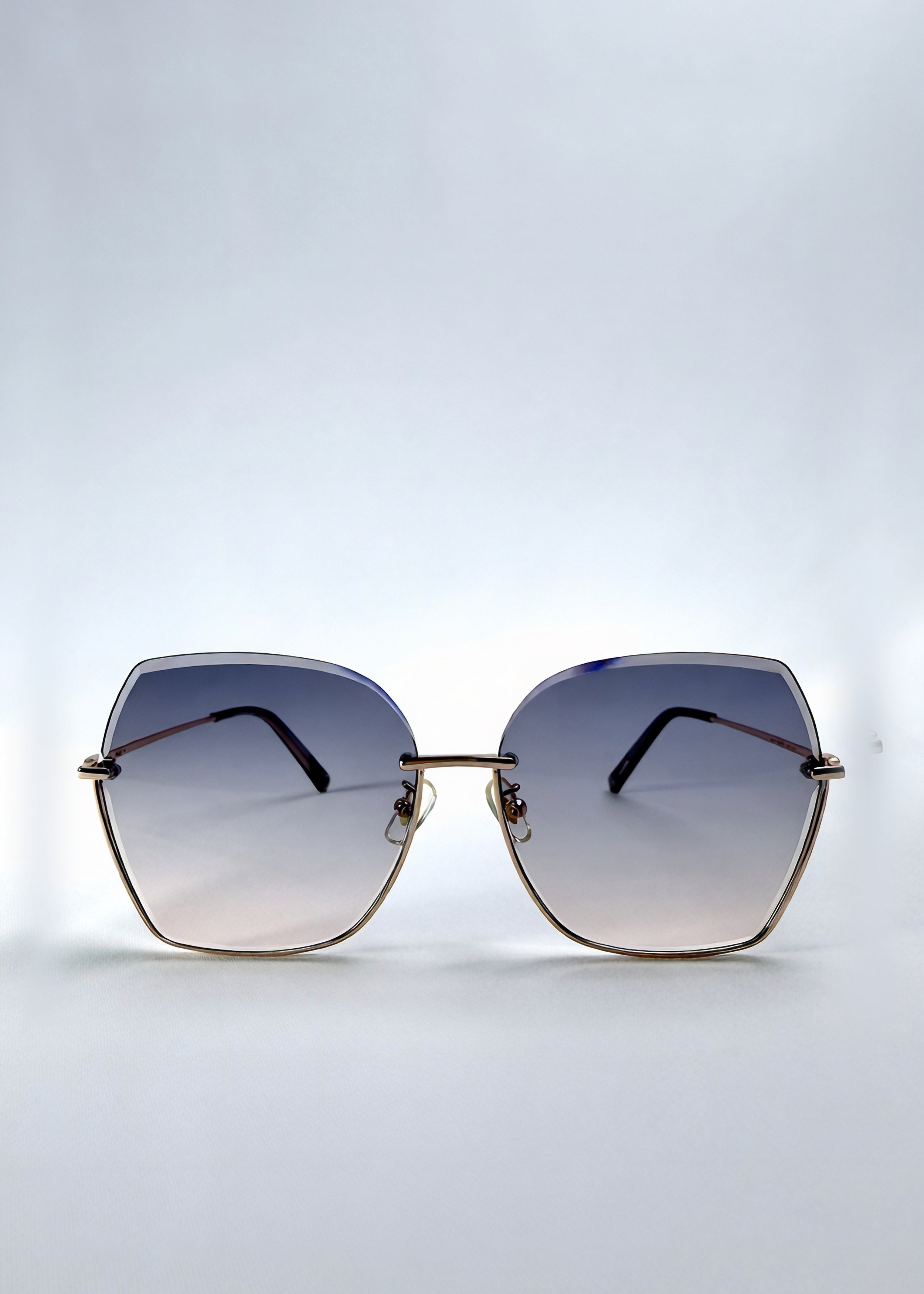 Front view of Aureon sunglasses in Rosé Quartz, featuring rimless metal frame, pale metal temples, and pink-grey gradient lenses, showing the full front silhouette.