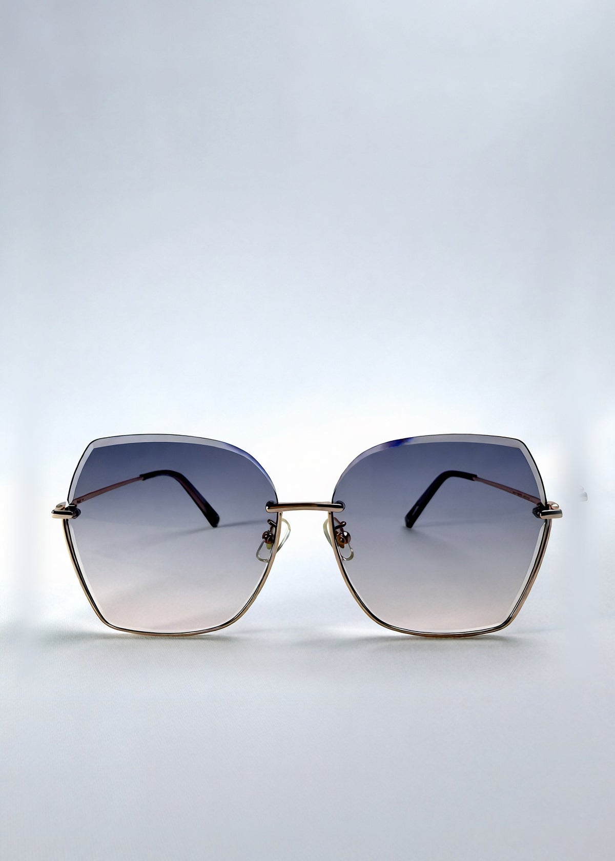 Front view of Aureon sunglasses in Rosé Quartz, featuring rimless metal frame, pale metal temples, and pink-grey gradient lenses, showing the full front silhouette.