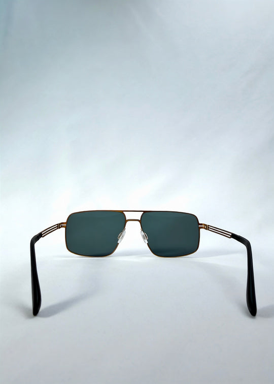 Back view of Axiom sunglasses in Antique Brass, featuring antique brass rectangular metal frame and green-grey polarized lenses, showing the inside frame and open temples. 