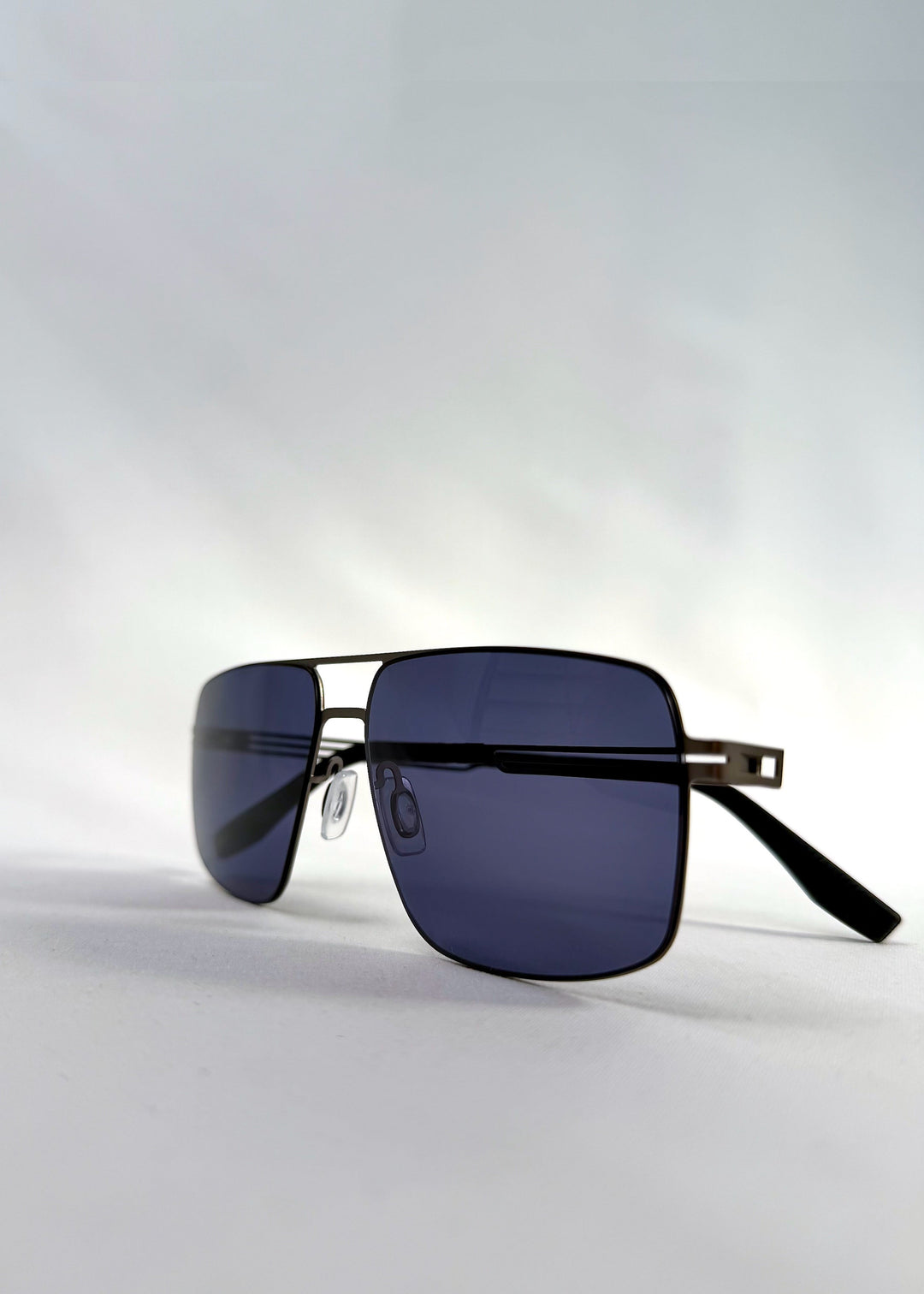 Side view of Axiom sunglasses in Blue Graphite, featuring blue-graphite rectangular metal frame and blue tinted polarized lenses, showing the lens shape and temple profile. 