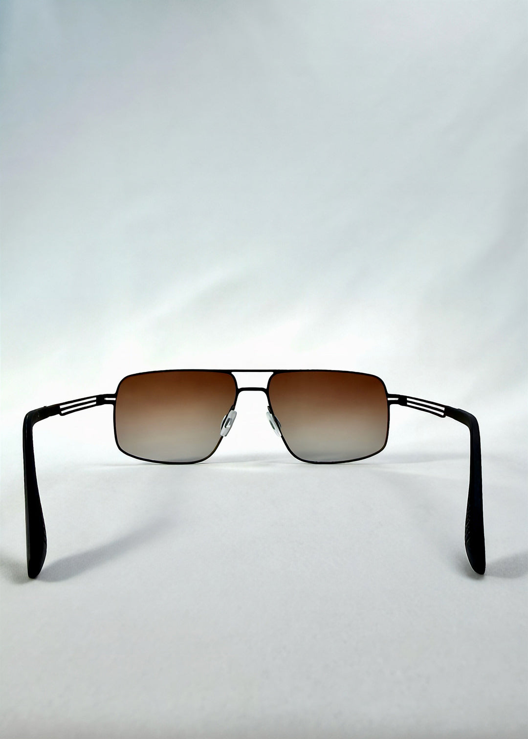 Back view of Axiom sunglasses in Eclipse Black, featuring dark rectangular metal frame and shadowed gradient polarized lenses, showing the inside frame and open temples. 