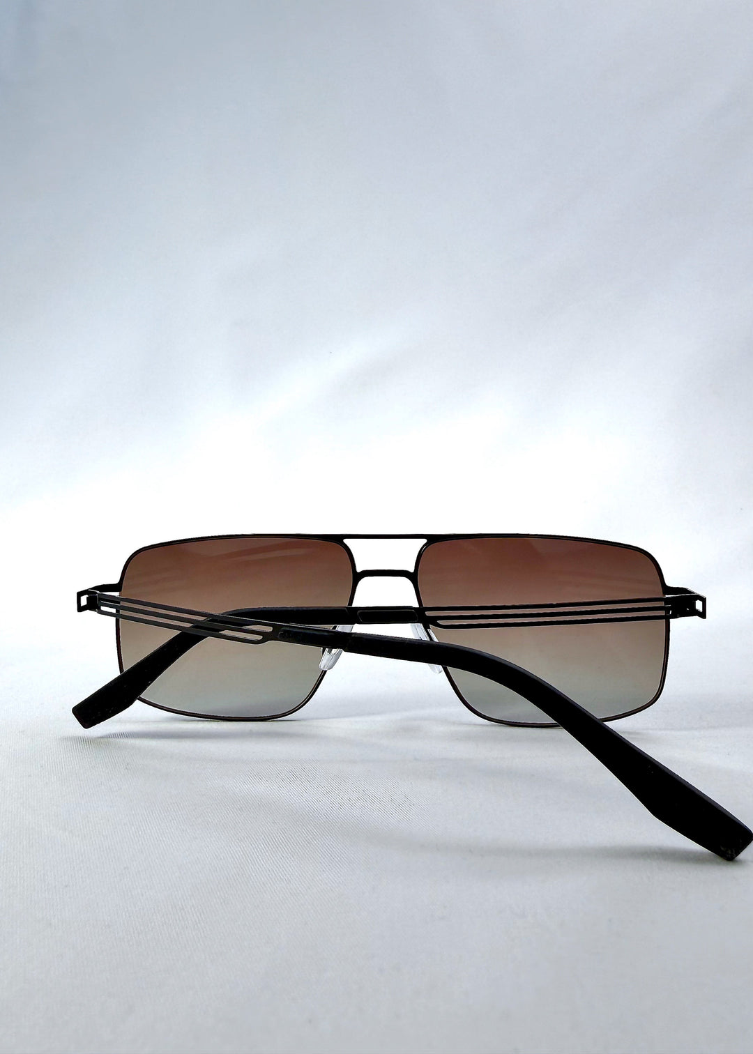 Folded view of Axiom sunglasses in Eclipse Black, featuring dark rectangular metal frame and shadowed gradient polarized lenses, showing the folded temples and frame profile. 