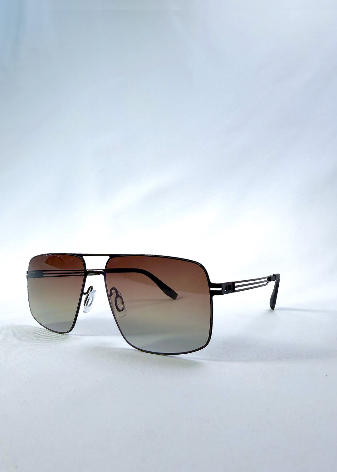 Three-quarter front view of Axiom sunglasses in Eclipse Black, featuring dark rectangular metal frame and shadowed gradient polarized lenses, showing the front shape and temple profile. 