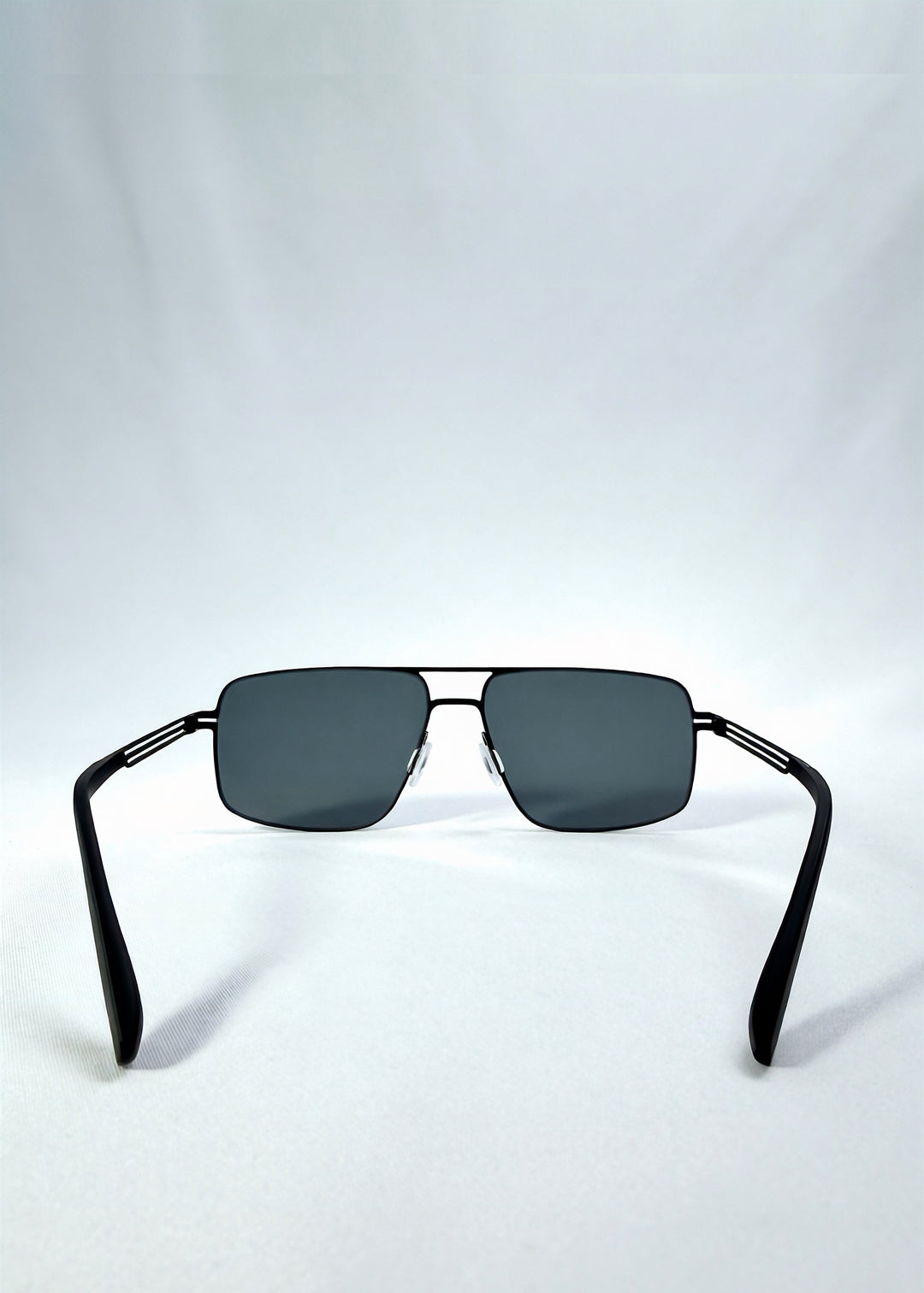 Back view of Axiom sunglasses in Matte Black, featuring matte black rectangular metal frame and grey polarized lenses, showing the inside frame and open temples. 