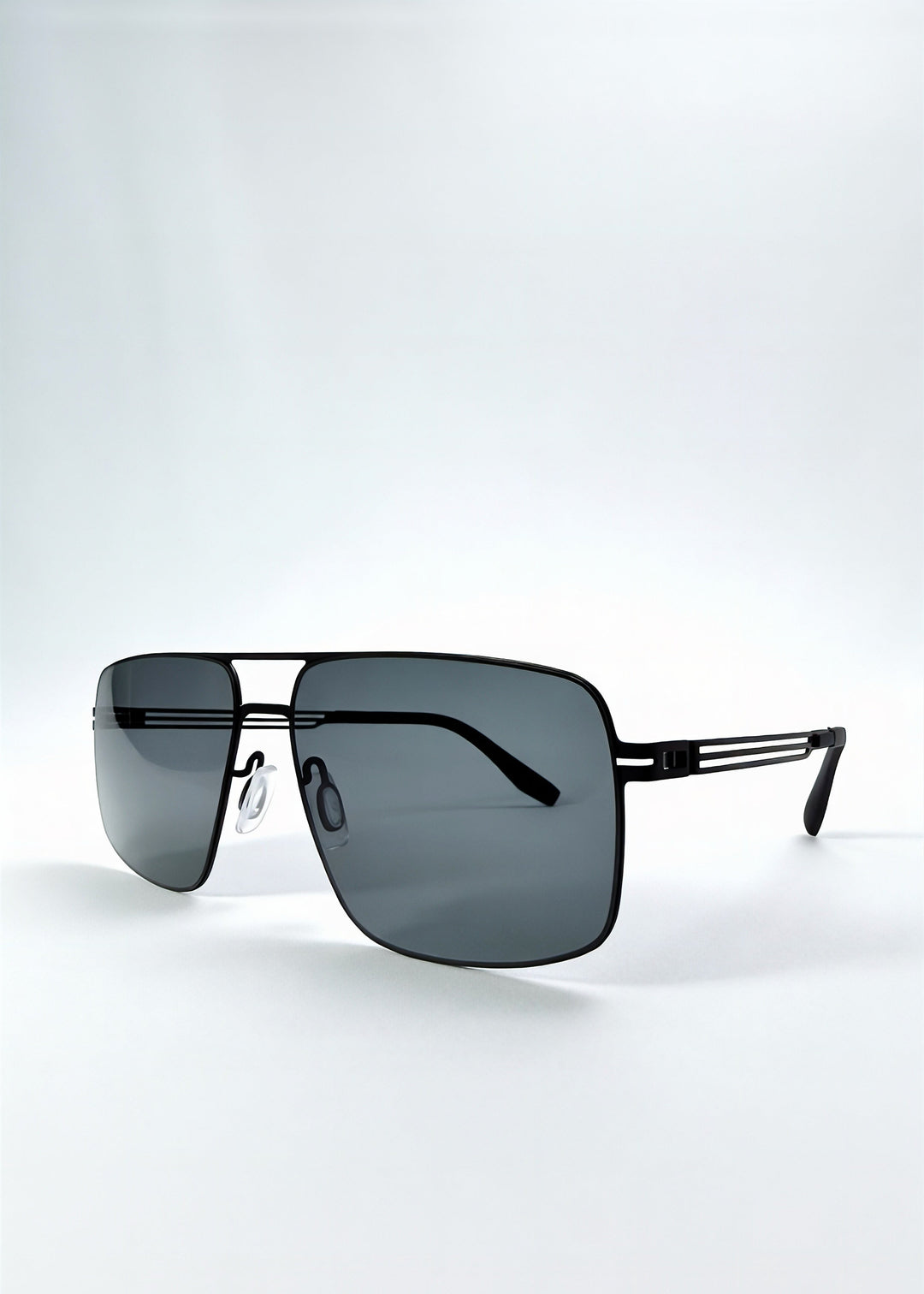 Three-quarter front view of Axiom sunglasses in Matte Black, featuring matte black rectangular metal frame and grey polarized lenses, showing the front shape and temple profile. 