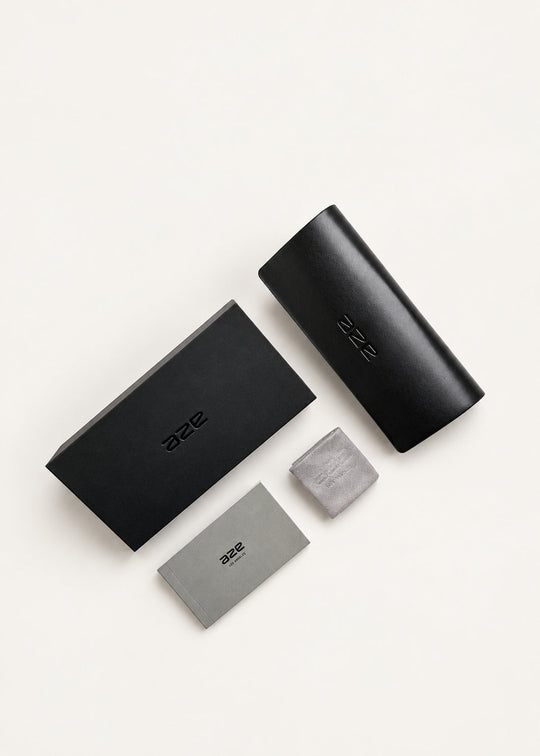 AZE Vault packaging for Aster Line sunglasses in Obsidian Black: black presentation box, protective eyewear case, cleaning cloth and care booklet.