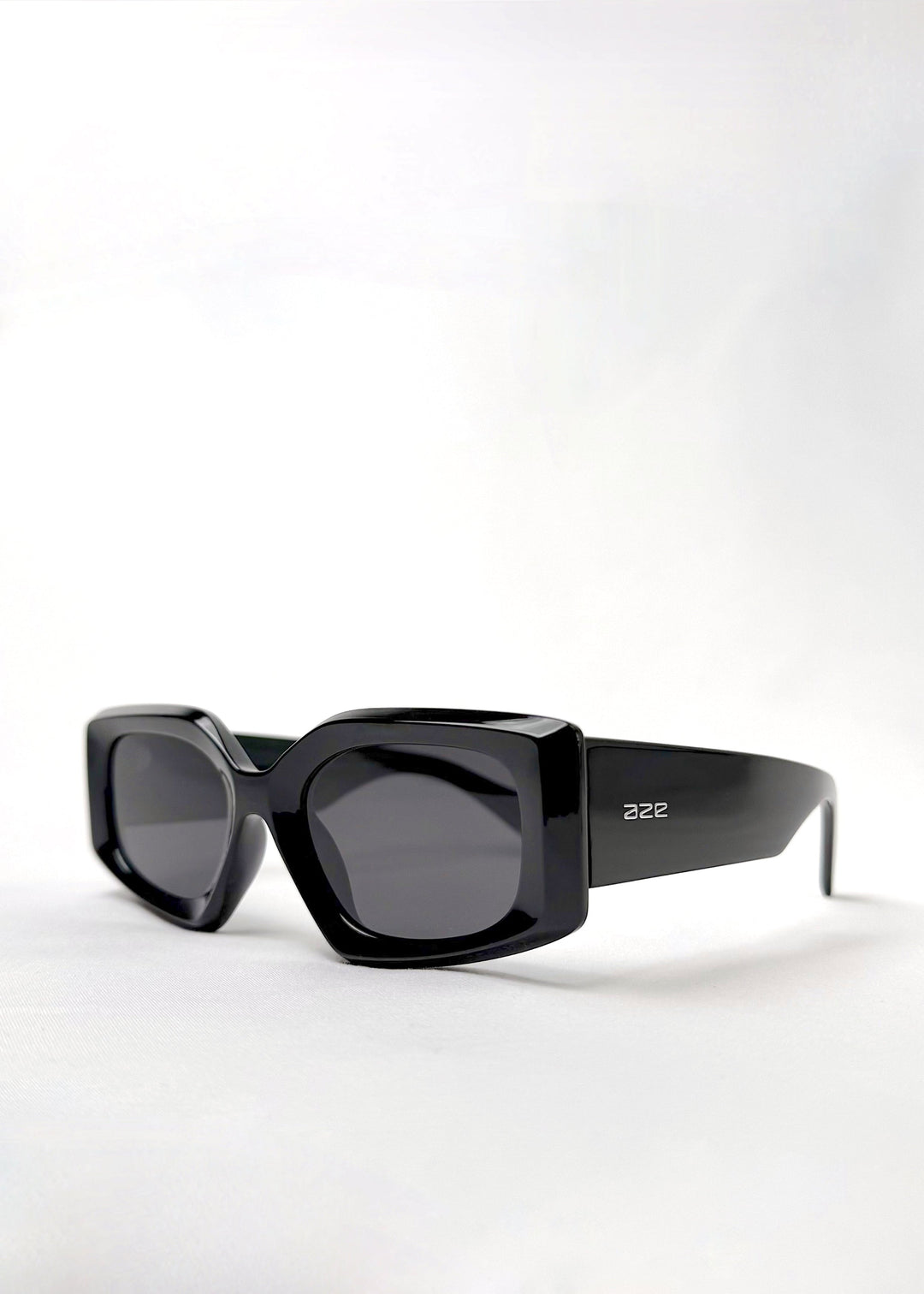Angled view of Bellatrix black acetate sunglasses featuring a bold oversized frame with high-gloss finish and UV400 polarized lenses. 
