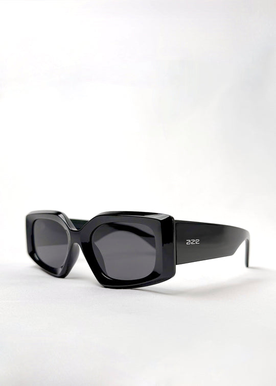 Angled view of Bellatrix black acetate sunglasses featuring a bold oversized frame with high-gloss finish and UV400 polarized lenses. 