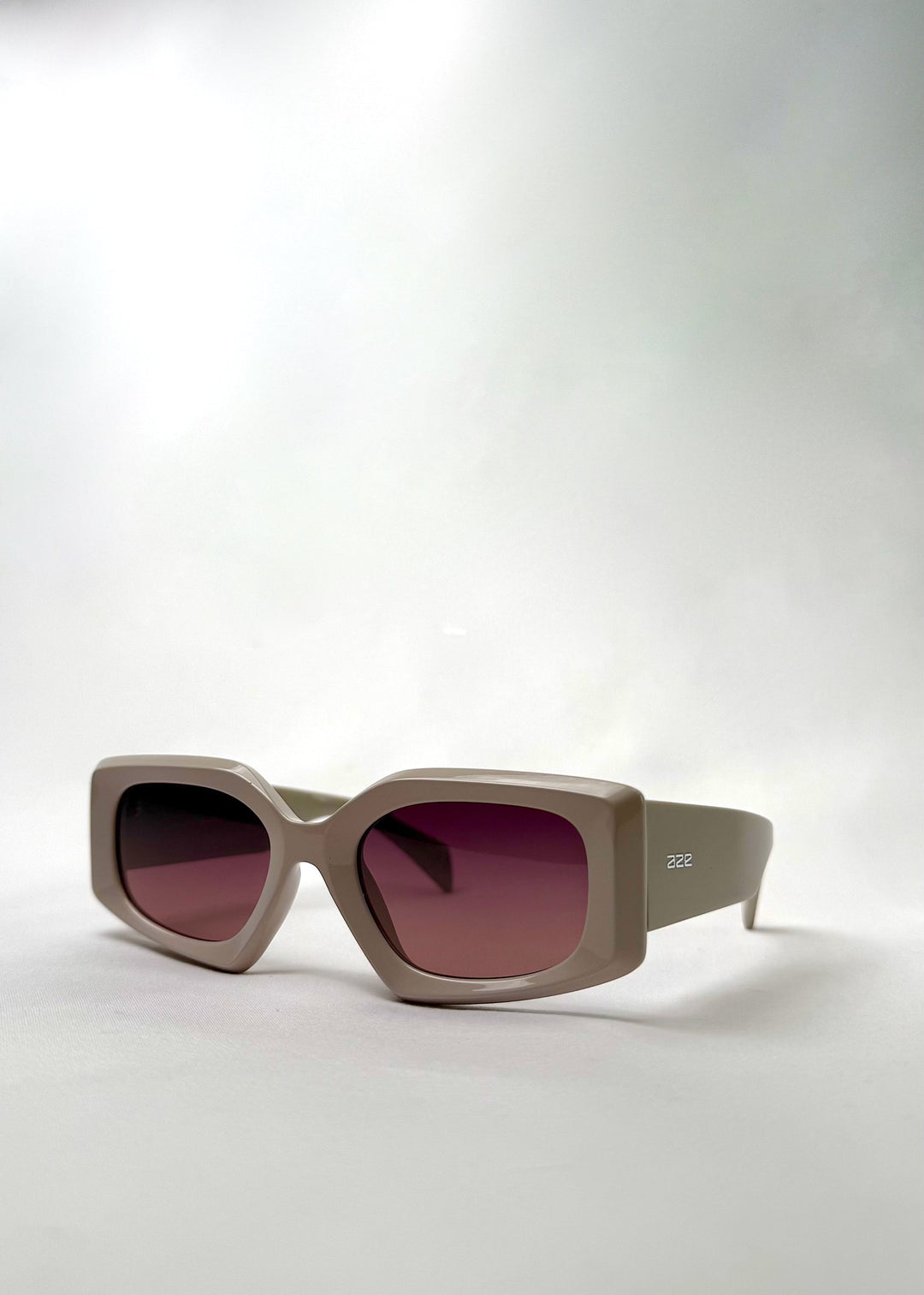 Angled view of Bellatrix warm taupe acetate sunglasses, highlighting the bold silhouette and neutral-tone frame. 