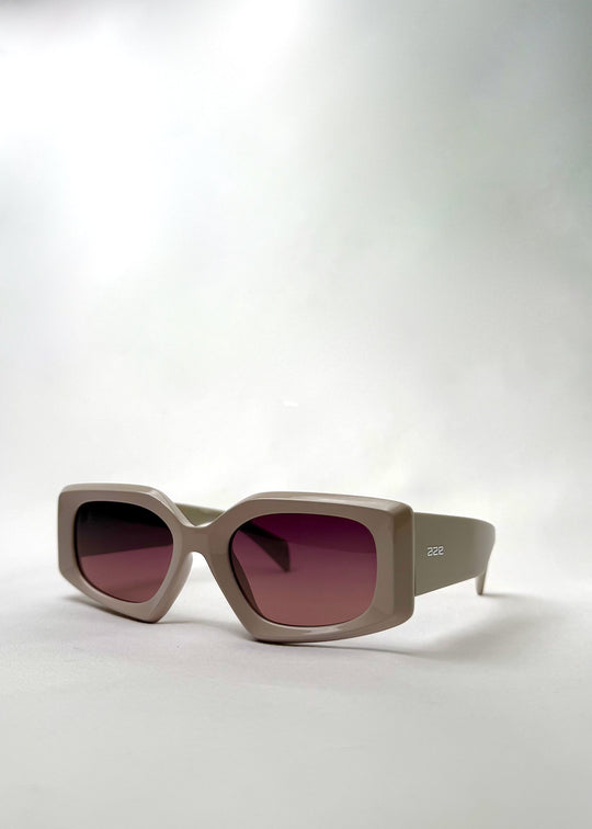 Angled view of Bellatrix warm taupe acetate sunglasses, highlighting the bold silhouette and neutral-tone frame. 