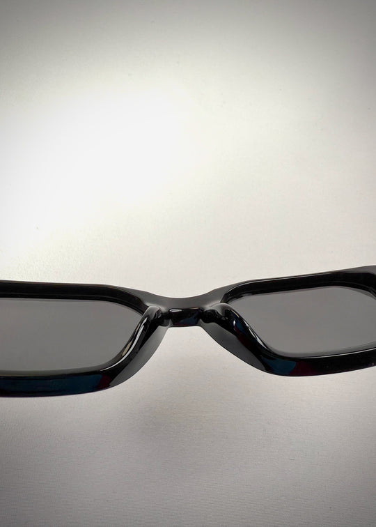 Close-up view of the nose bridge on Castor Black acetate prescription sunglasses, showcasing the glossy black frame and precision craftsmanship. 