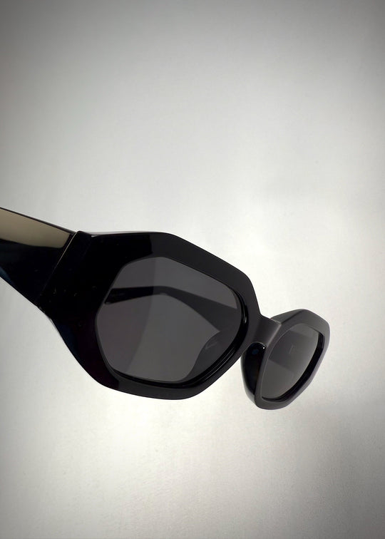 Angled view of Castor Black acetate prescription sunglasses, highlighting the bold geometric design and dark polarized lenses. 