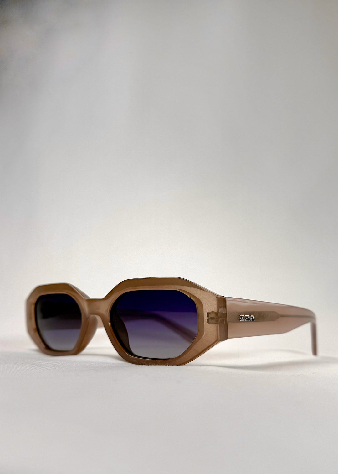 Close-up of Castor Champagne sunglasses, showing gradient blue lenses and refined craftsmanship. 