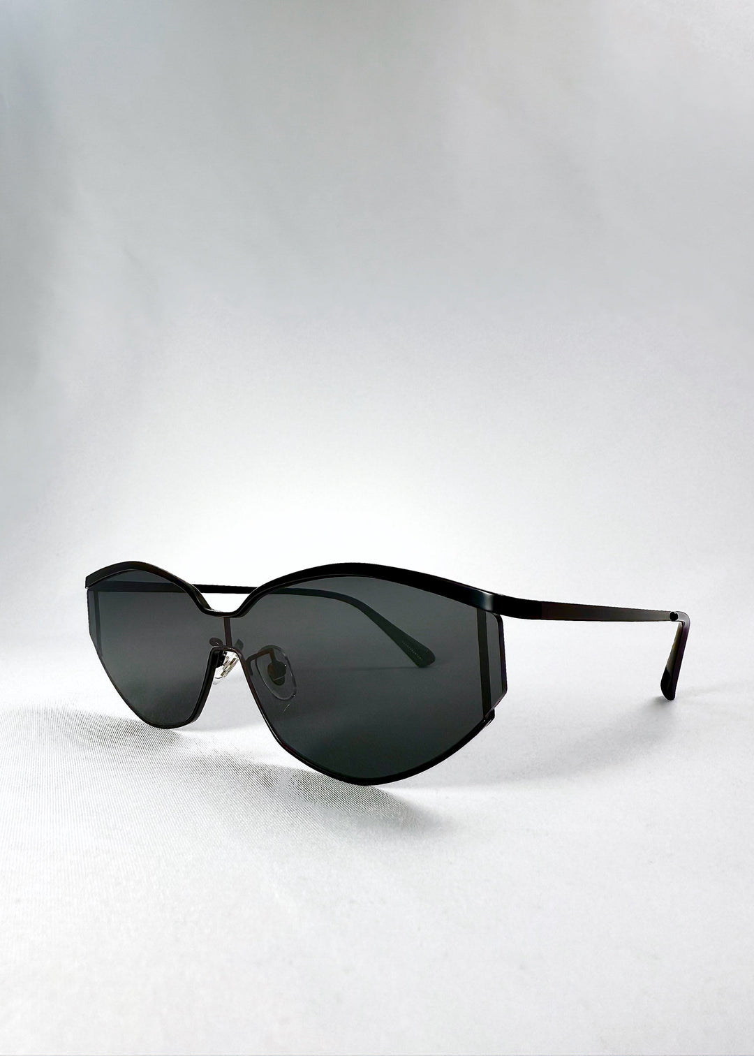 Angled front view of Celestia – Matte Black sunglasses displaying the futuristic cat-eye silhouette and minimalist matte finish.
