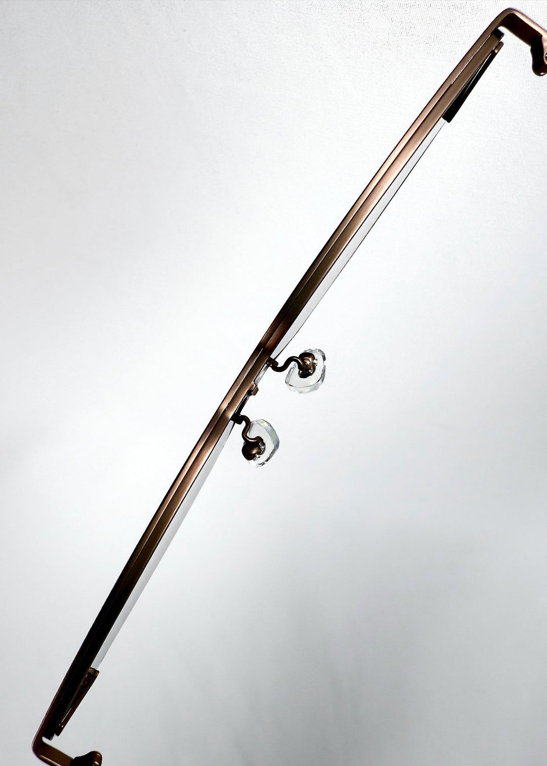 Close-up of the adjustable nose pads on Celestia – Mocha Bronze, showing the clear pads and the bronze metal browline bar. 