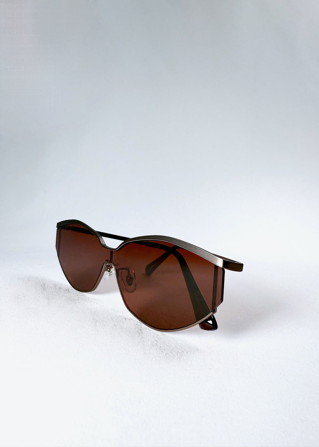 Angled view of the Celestia – Ruby Smoke sunglasses in a semi-folded position, displaying the fluid frame shape and subtle shine. 