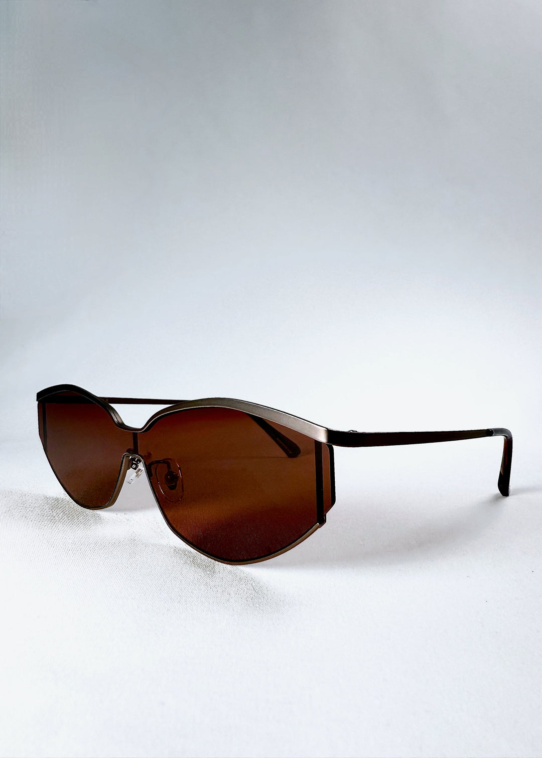 Front angle view of Celestia – Ruby Smoke highlighting the champagne-silver metal browline and rust-red HD nylon lenses. 