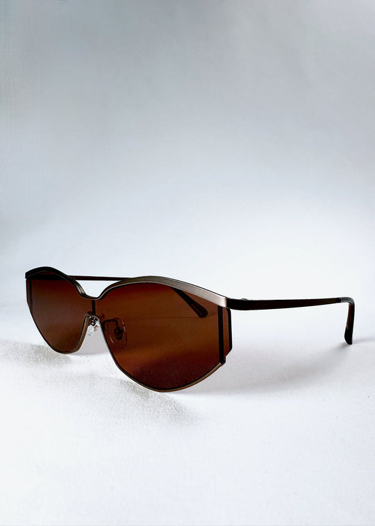 Front angle view of Celestia – Ruby Smoke highlighting the champagne-silver metal browline and rust-red HD nylon lenses. 