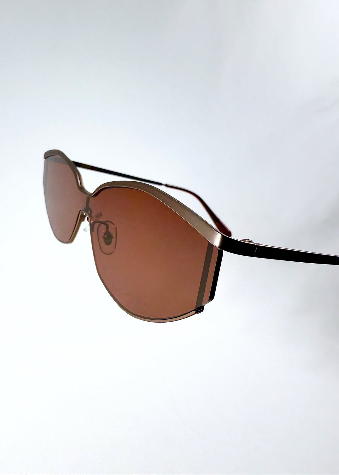 Detail of the lens and frame edge on Celestia – Ruby Smoke, showing the brushed metal finish and seamless lens transition. 