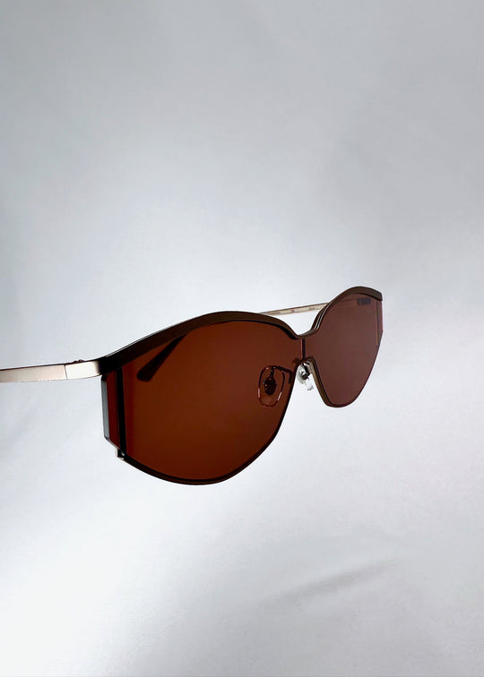 Side profile of Celestia – Ruby Smoke showing the slim champagne-silver metal temples and the rust-red lens edge. 