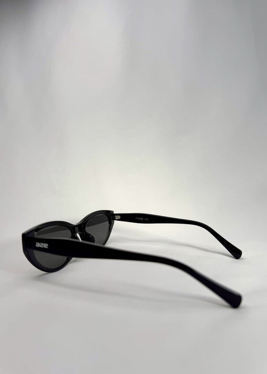 Side-angle view of Chara sunglasses in Black, featuring a glossy black cat-eye acetate frame and UV400 lenses, showing the lens shape and temple profile. 
