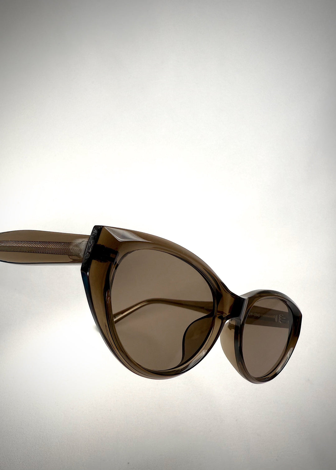 Side-angle view of Chara sunglasses in Champagne Brown, featuring a translucent champagne brown cat-eye acetate frame and UV400 lenses, showing the lens shape and temple profile. 