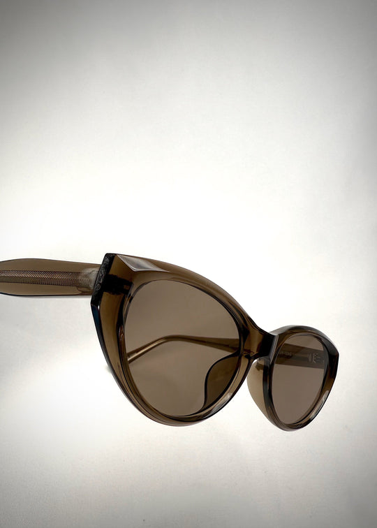 Side-angle view of Chara sunglasses in Champagne Brown, featuring a translucent champagne brown cat-eye acetate frame and UV400 lenses, showing the lens shape and temple profile. 