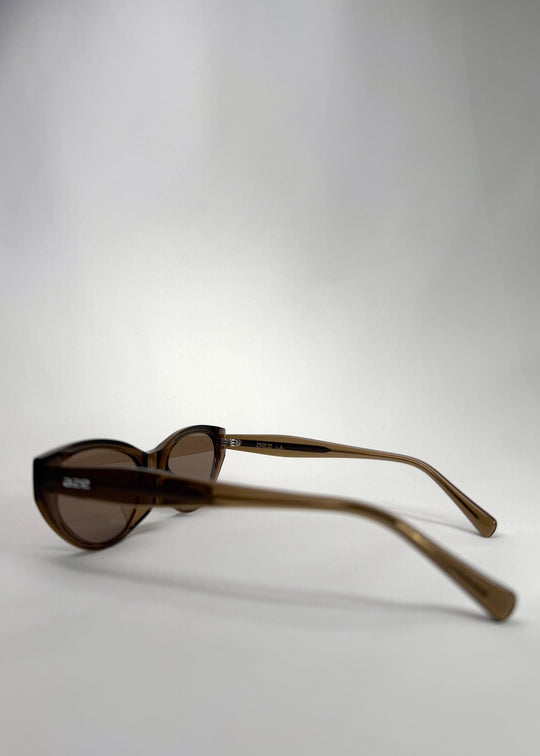 Side view of Chara sunglasses in Champagne Brown, featuring a translucent champagne brown cat-eye acetate frame and UV400 lenses, showing the temple arms and frame profile. 