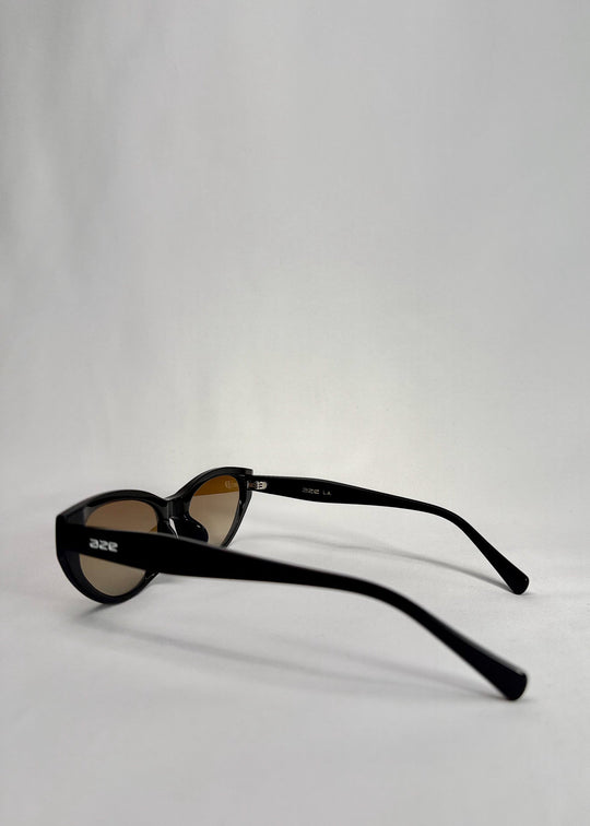 Side-angle view of Chara sunglasses in Gradient Amber, featuring a glossy black cat-eye acetate frame with amber gradient lenses, showing the lens shape and temple profile. 