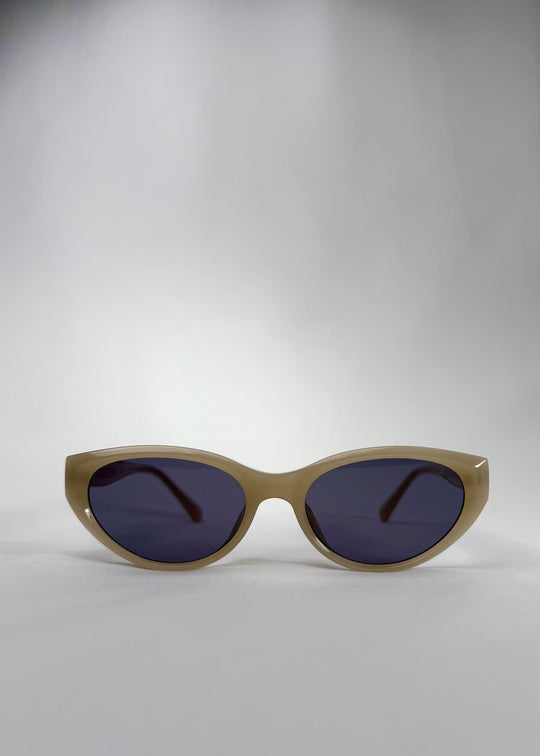 Front view of Chara sunglasses in Milky White, featuring a translucent ivory cat-eye acetate frame and deep blue lenses, showing the full front silhouette. 