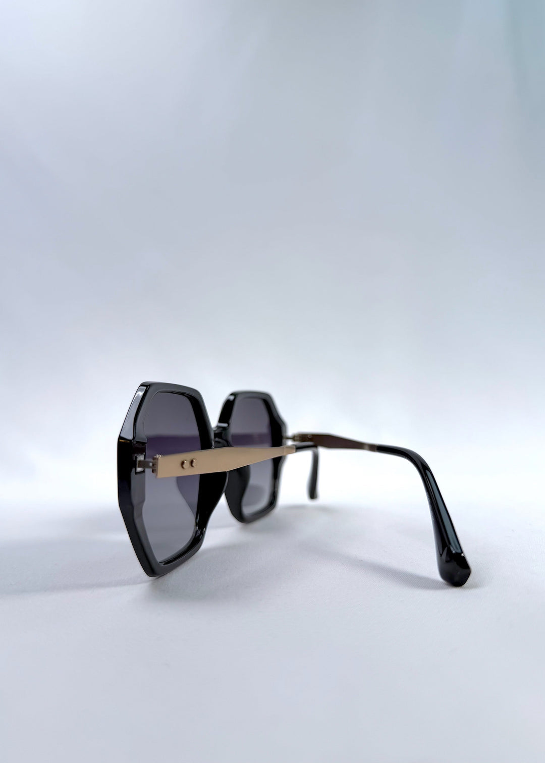 Back-angle view of Ciel Arc sunglasses in Duskgold, featuring black and gold frame with dark lenses, showing the back structure and temple alignment. 